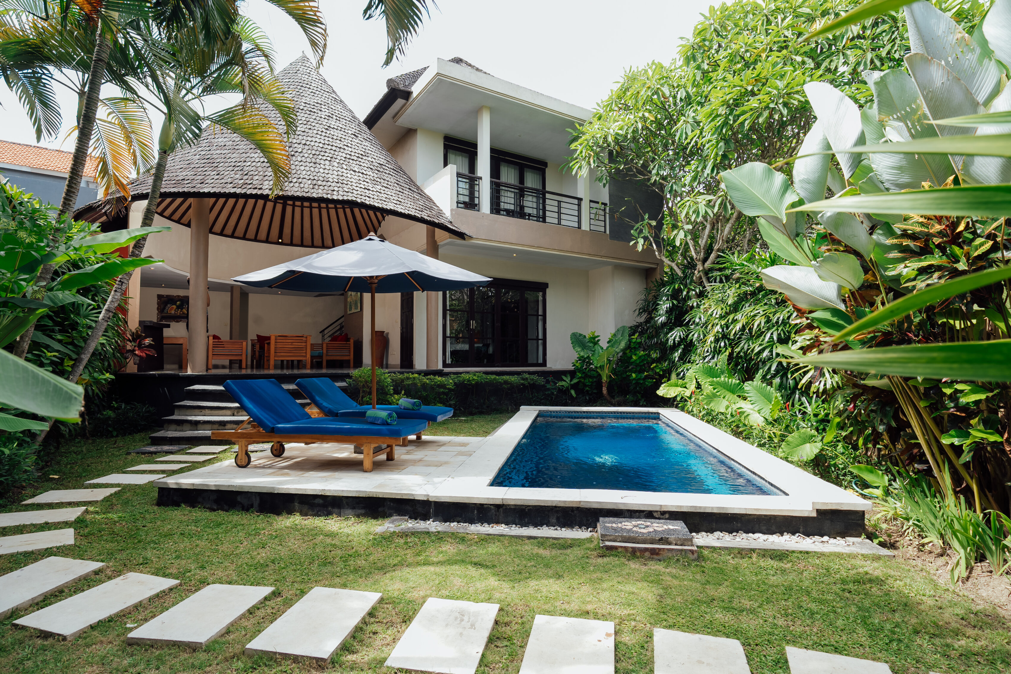 Private pool villa exterior with blue parasol and sun loungers, The Bidadari