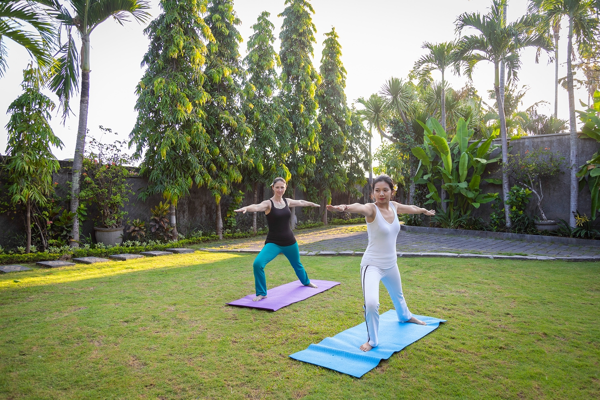 Two guests practising yoga on mats in the garden, The Bidadari Villas & Spa